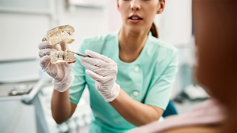 Nahaufnahme einer Zahnärztin, die ihrem Patienten während eines Zahnarzttermins das Verfahren für Zahnimplantate erklärt Nahaufnahme einer Zahnärztin, die ihrem Patienten während eines Zahnarzttermins das Verfahren für Zahnimplantate erklärt
