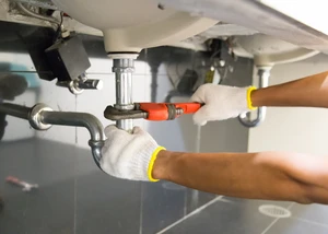 Plumber fixing white sink pipe with adjustable wrench. Rohrreinigung, Rohre, Sanierung, Werkzeug, abschrauben, Baustelle