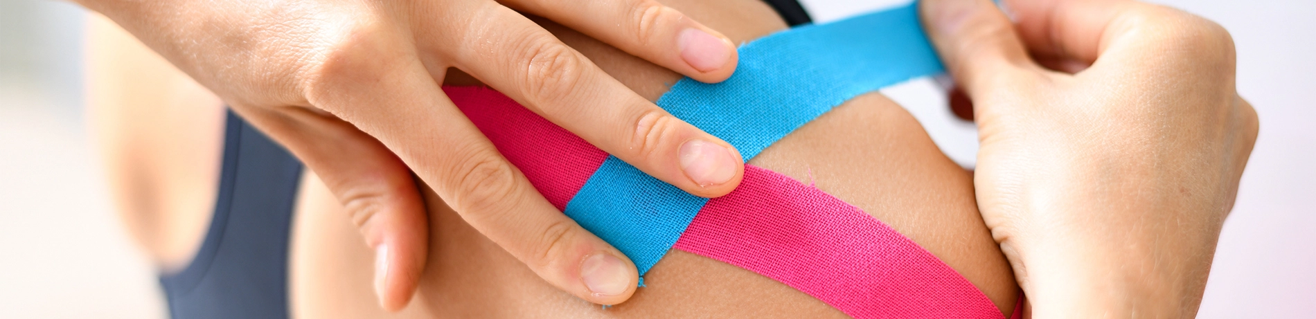 Kinesio Taping Behandlung mit blauen und rosa Band auf Patientin mit verletzter Schulter