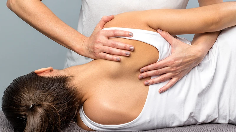 Physiotherapeut behandelt das Schulterblatt einer Patientin Physiotherapeut behandelt das Schulterblatt einer Patientin