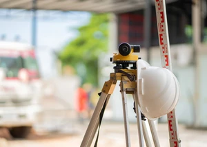 Ingenieurs-Nivellierkamera und ein weißer Kunststoffhelm auf einer Baustelle Ingenieurs-Nivellierkamera und ein weißer Kunststoffhelm auf einer Baustelle